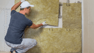 homme qui pose de l'isolation sur un mur intérieur